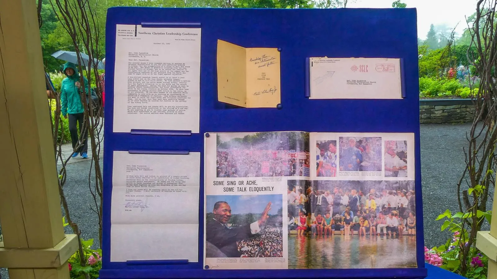 A letter, newspaper clippings, and envelope mounted on a blue display board.