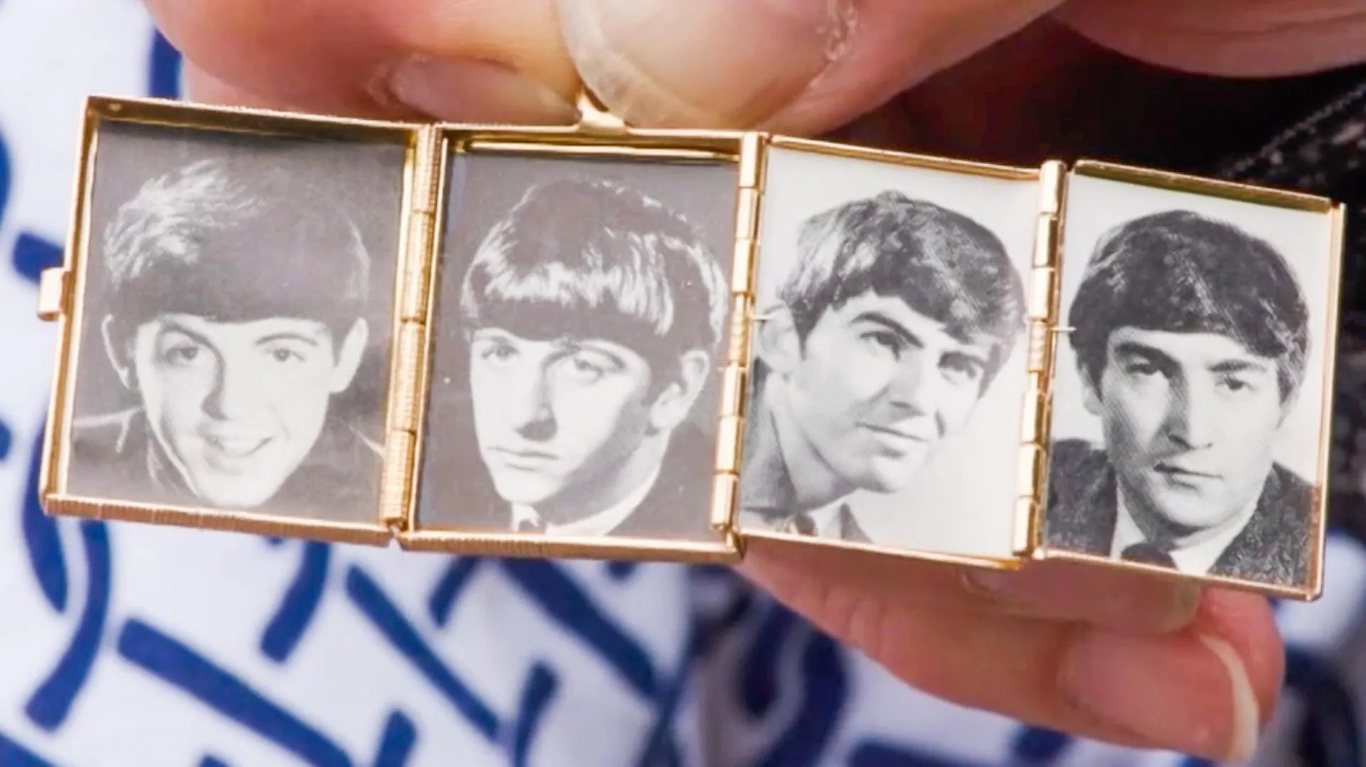 A close up of a gold fold out locket with each section having a portrait of each Beatles member.