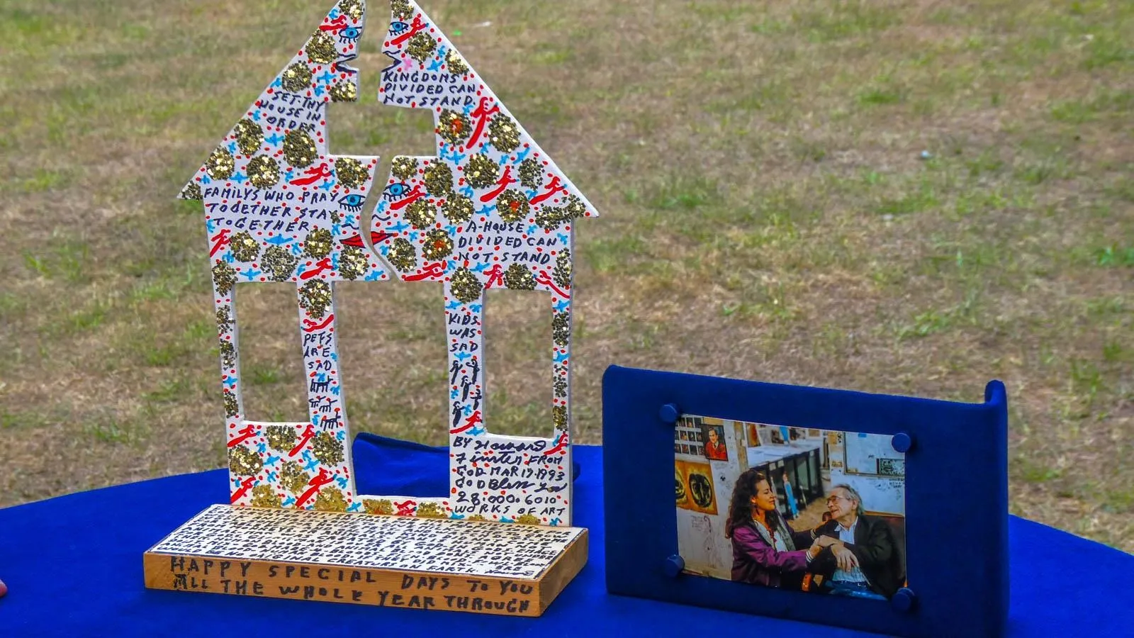 Close up of a house shaped figure decorated with black red and blue drawings and gold glittered polka dots.
