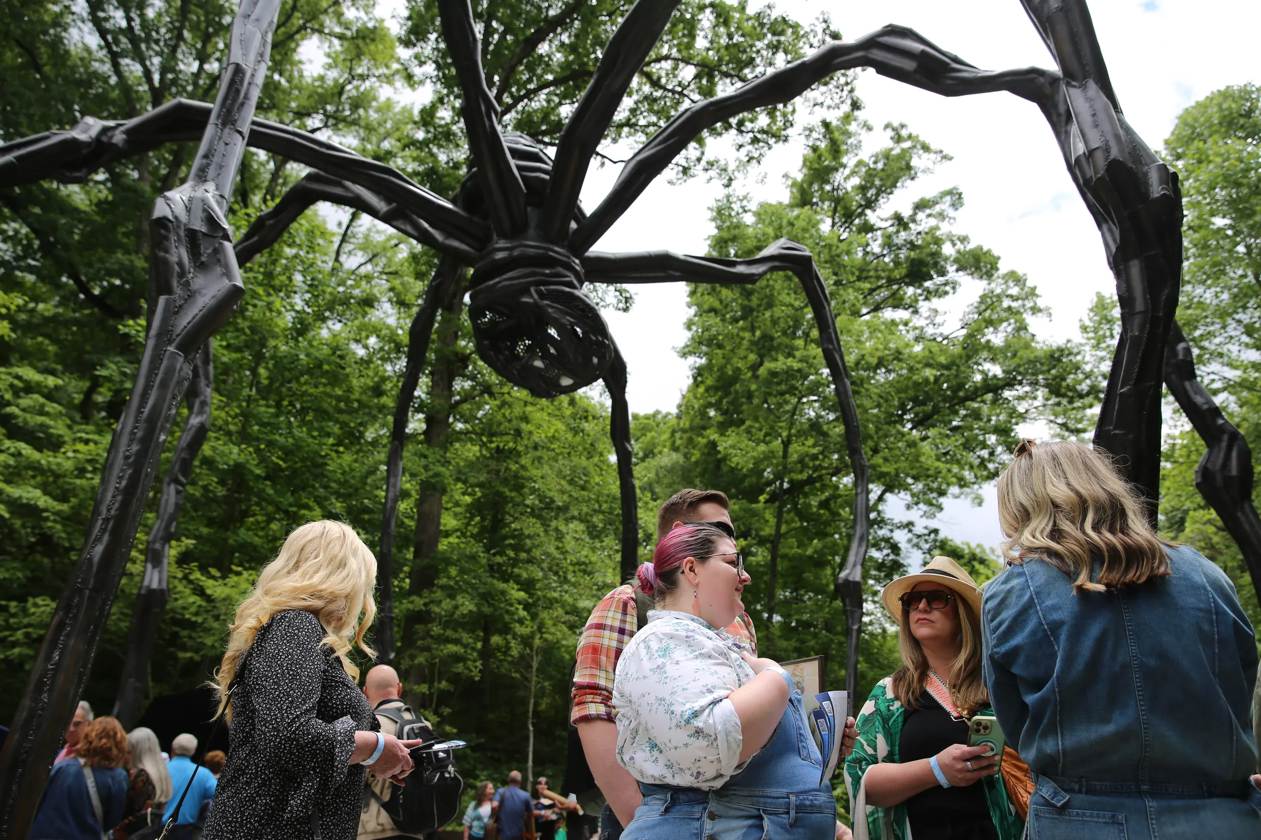 A crowd gathers below a giant spider-statue, one of the many staples of Crystal Bridges' outdoor art collection.