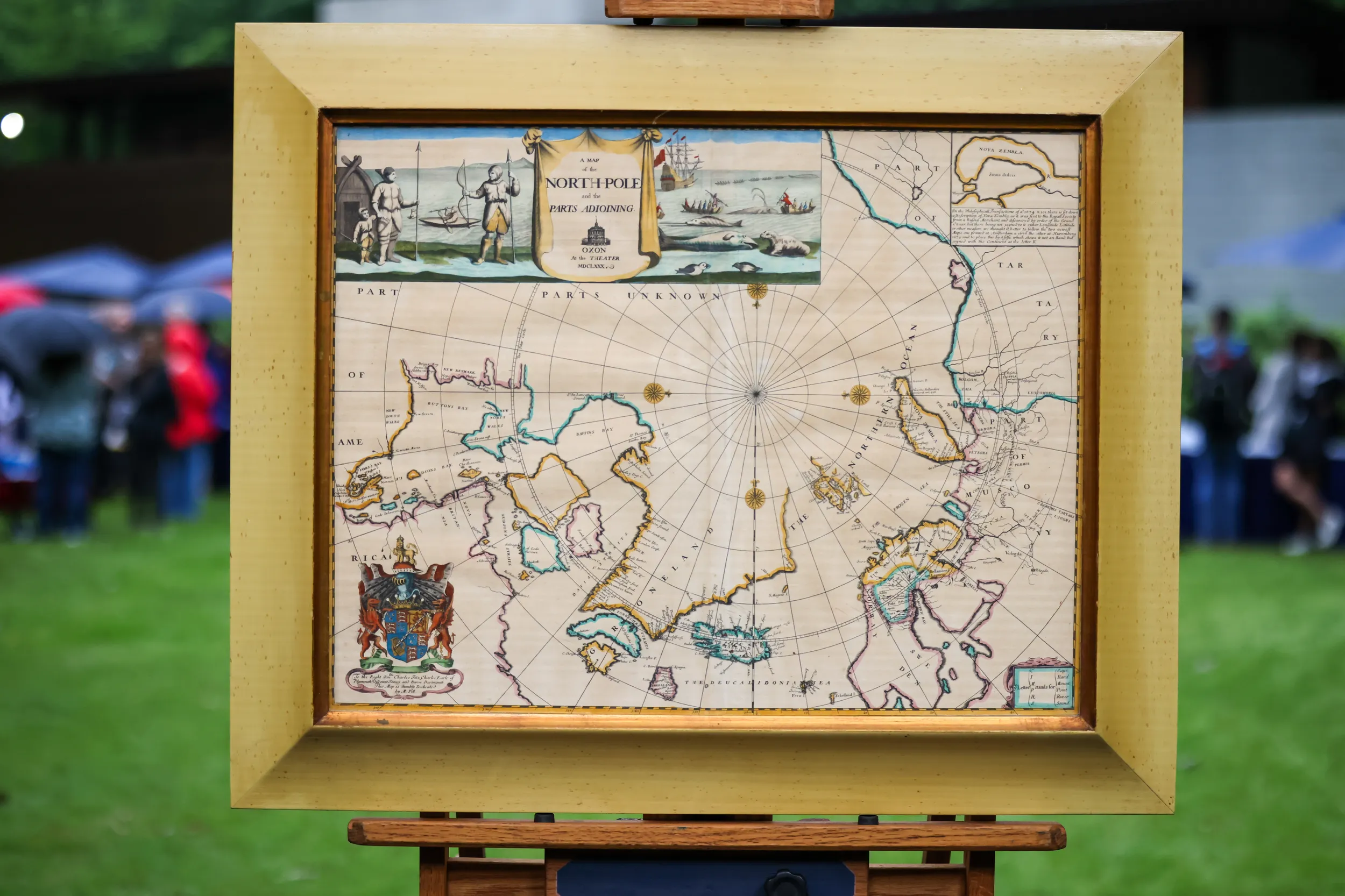 Framed map of the north pole from 1680. Land masses and routes are highlighted in pink, yellow, and blue.