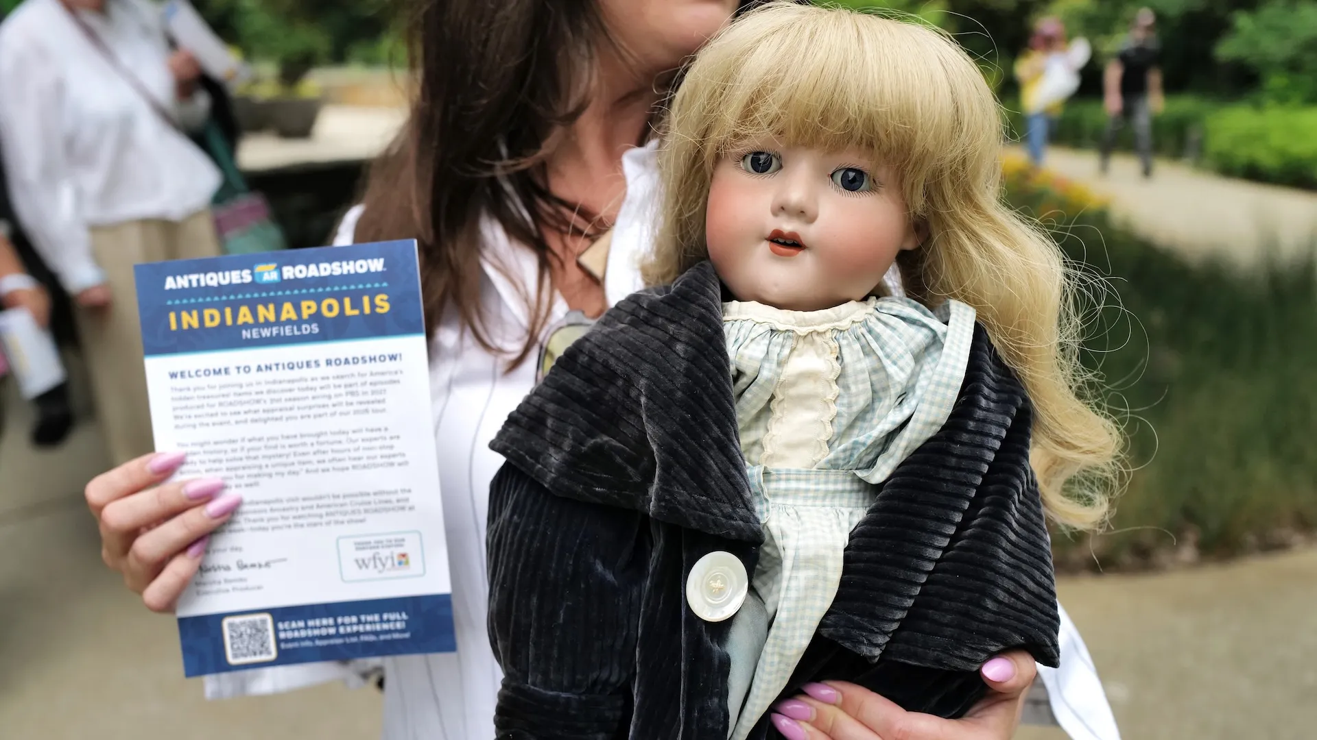 A photo of a guest holding a doll and info sheet