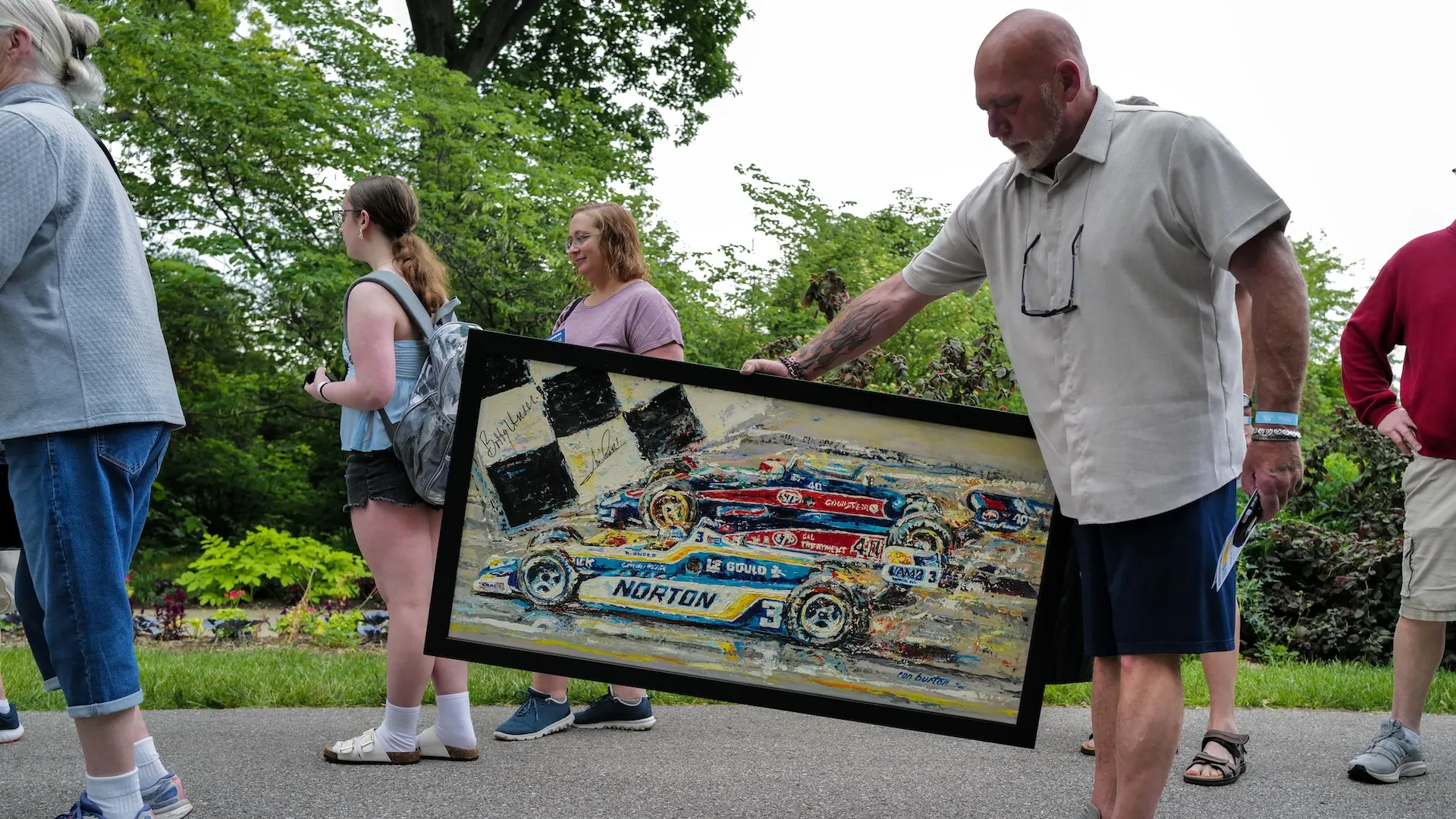 A photo of a guest holding signed racing artwork