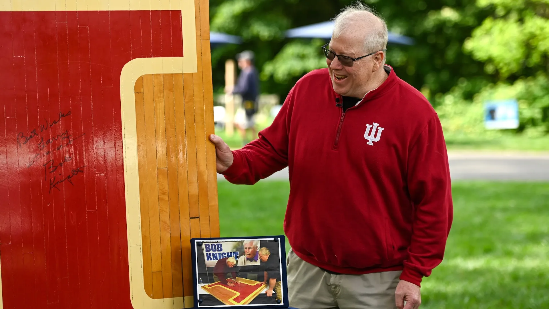 A guest standing next to a signed Indiana University court floor piece