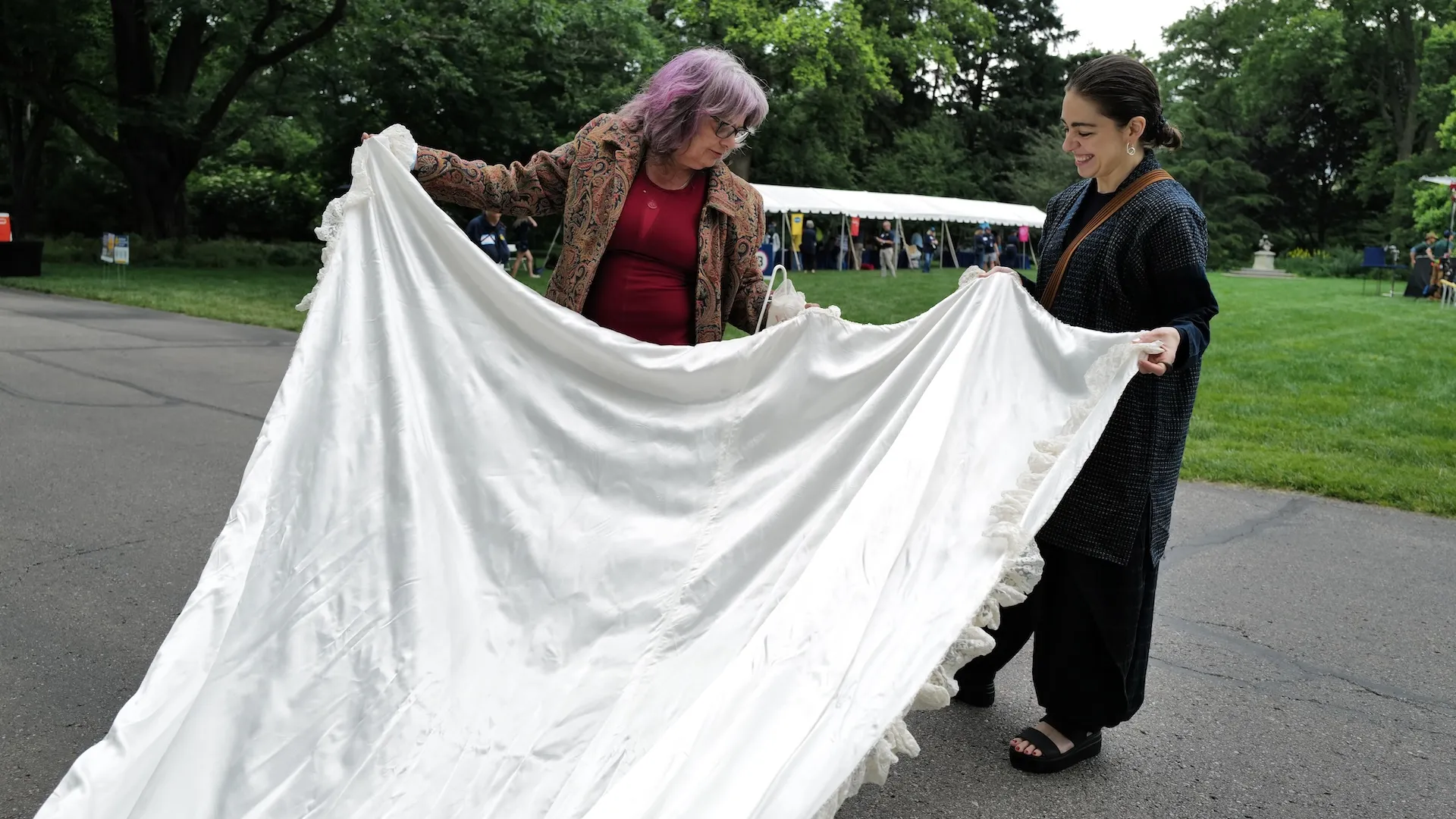 A photo of a guest and an appraiser examining a long wedding dress