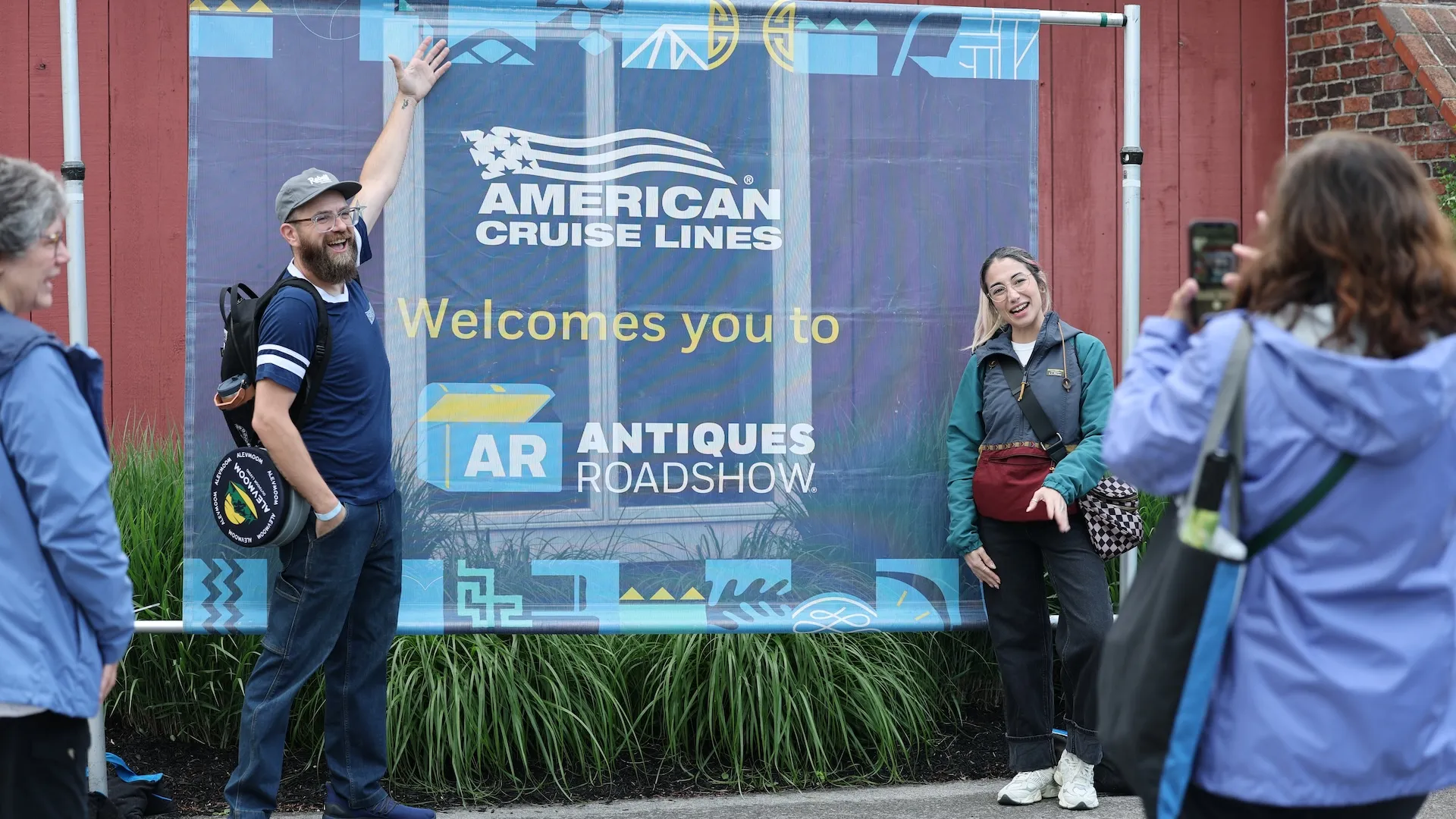 A photo of guests posing in front of a ROADSHOW photo wall