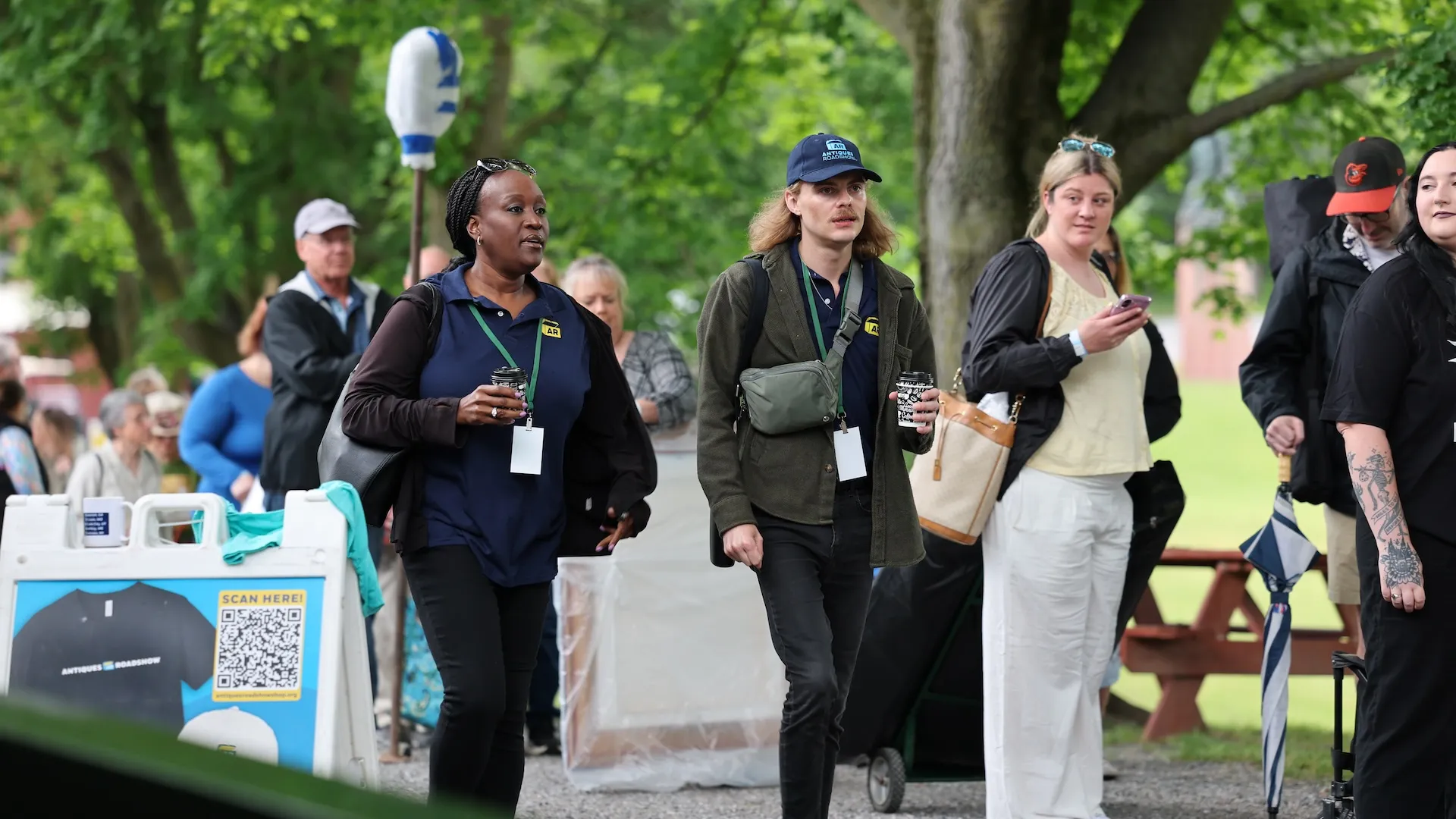 A photo of two volunteers walking amongst a line of guests