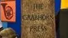 Close up of a wooden sign that says "The Grabhorn Press" against a multi colored background