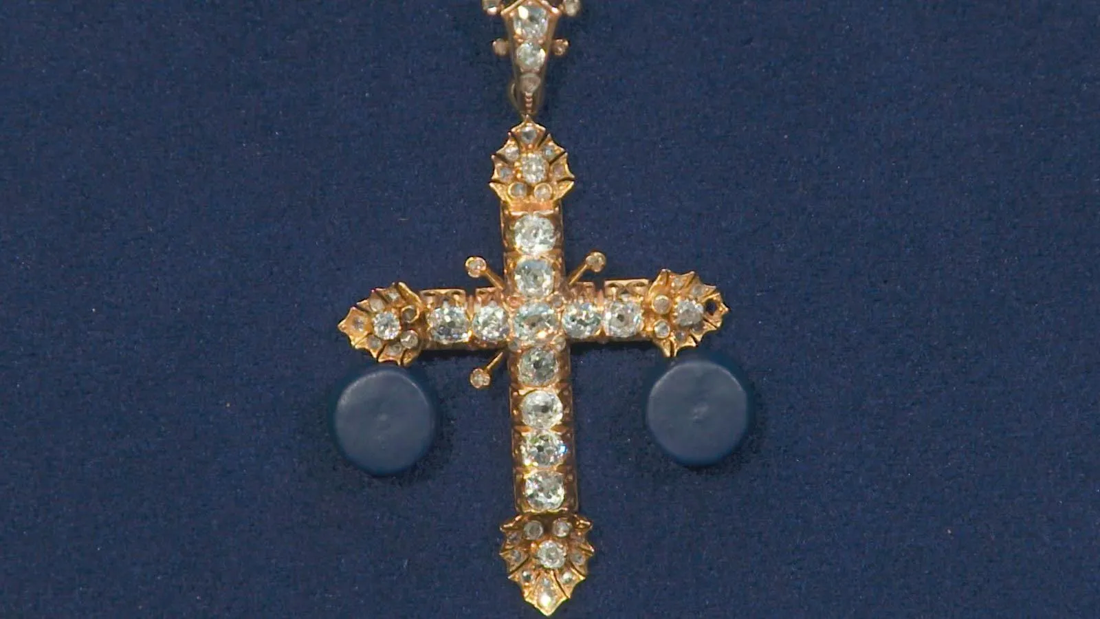 Close up of a gold cross with diamonds along it.