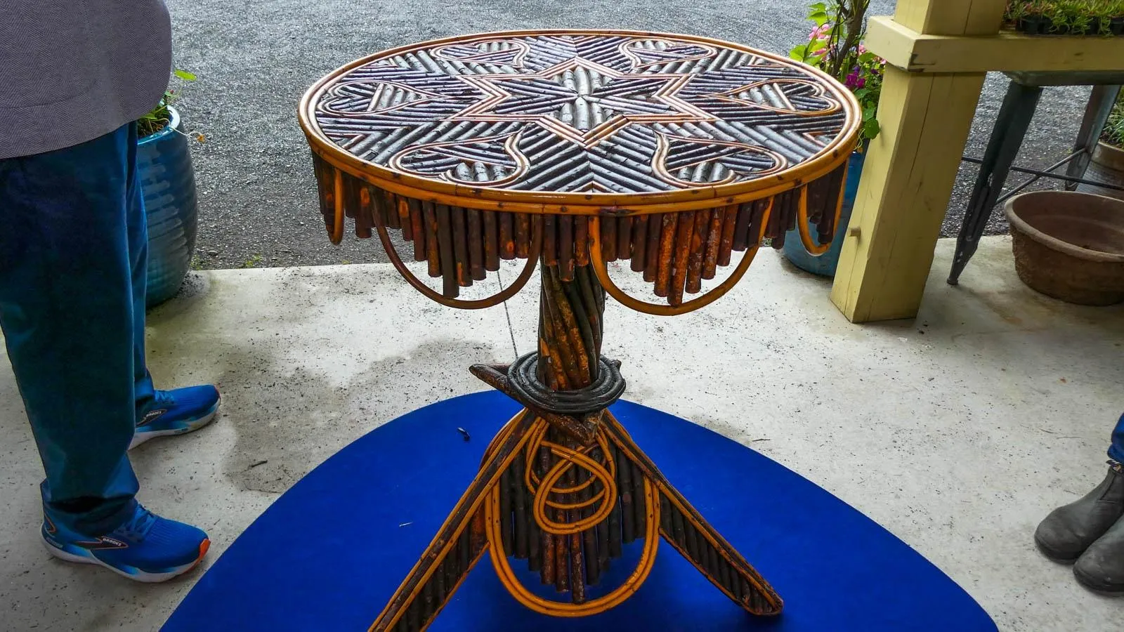 A table with heart and star designs made out of twigs placed on top of a blue platform with people standing around it.