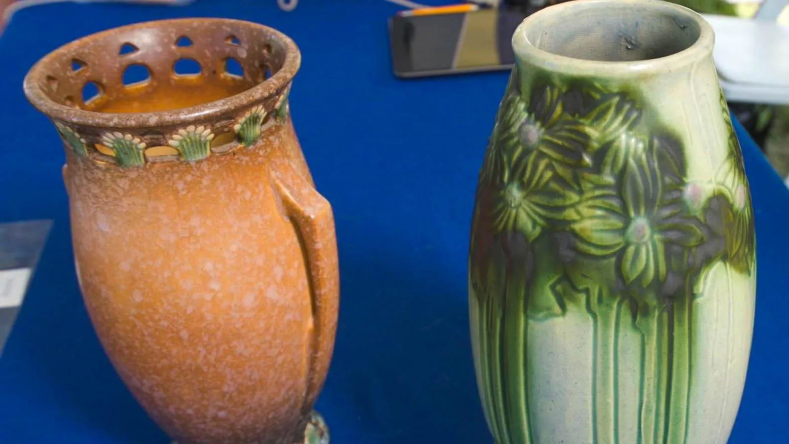 An orange and a green vase with glaze and painted detailing.