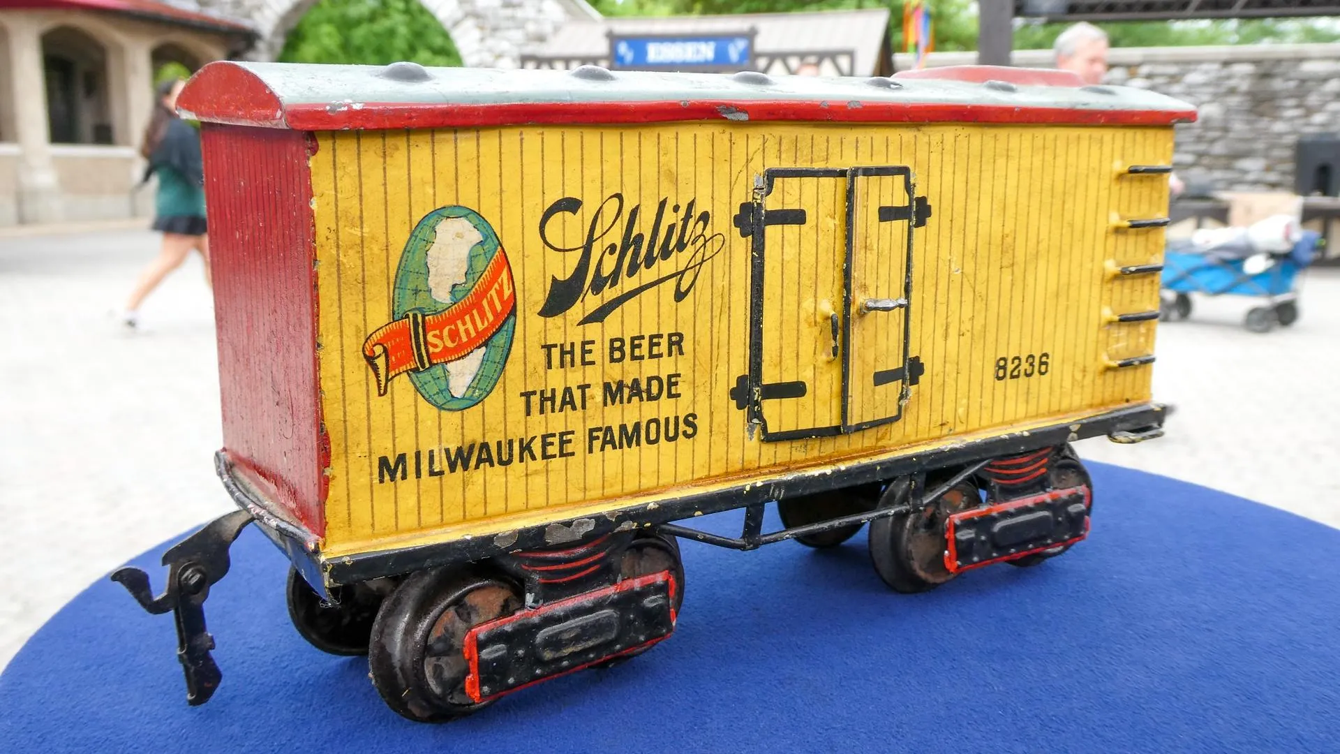 Close up of a small red and yellow tin train car with the Schlitz beer logo on the side placed on a table.