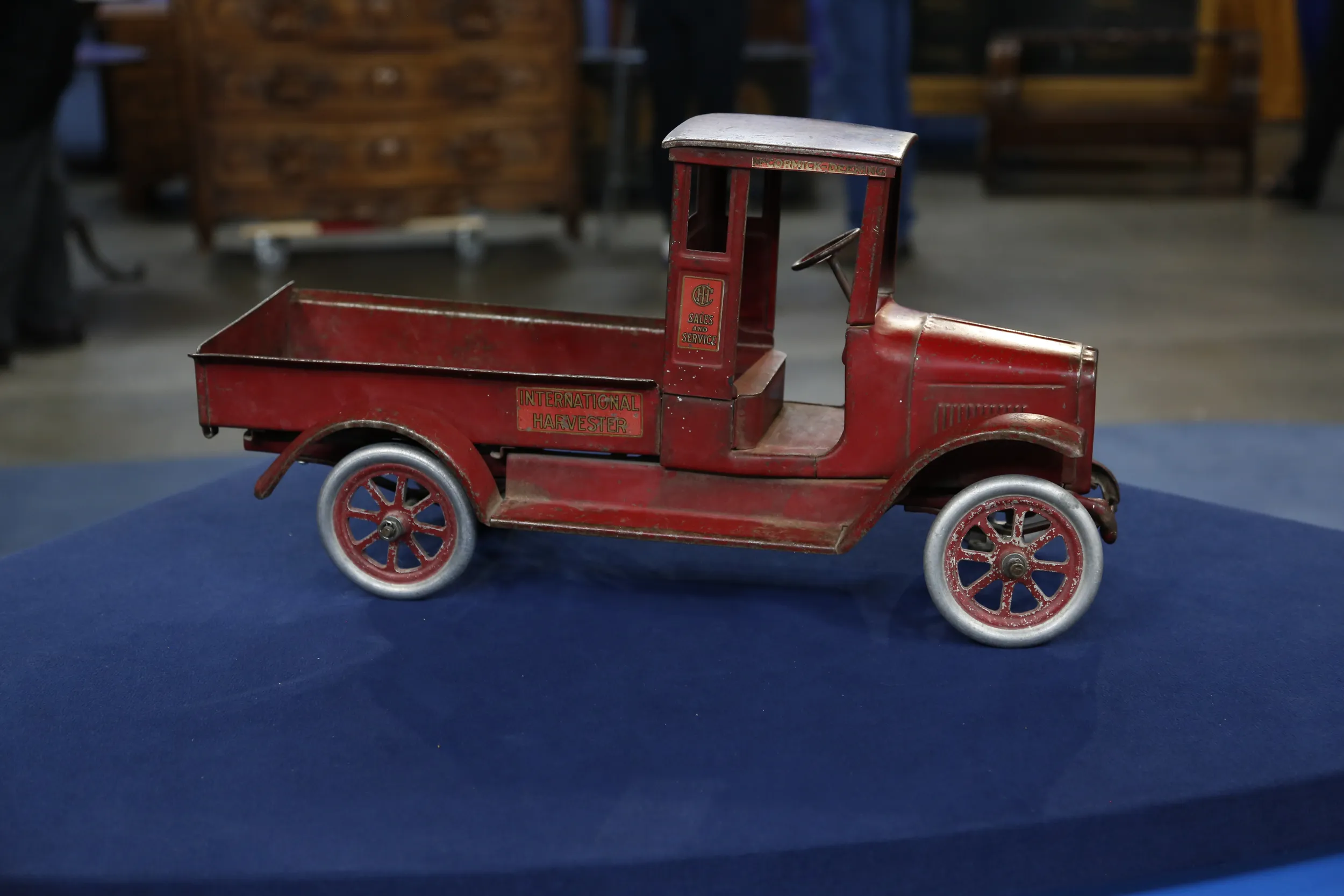 Small toy truck painted red and composed of steel. Side of truck bed reads "International Harvester."