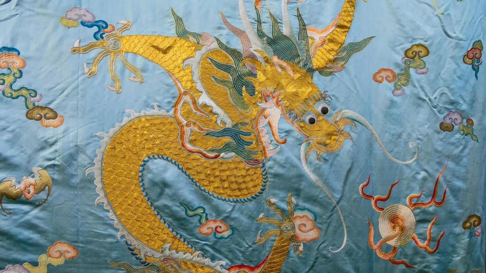 Close up on a blue silk panal with a yellow dragon in the center.