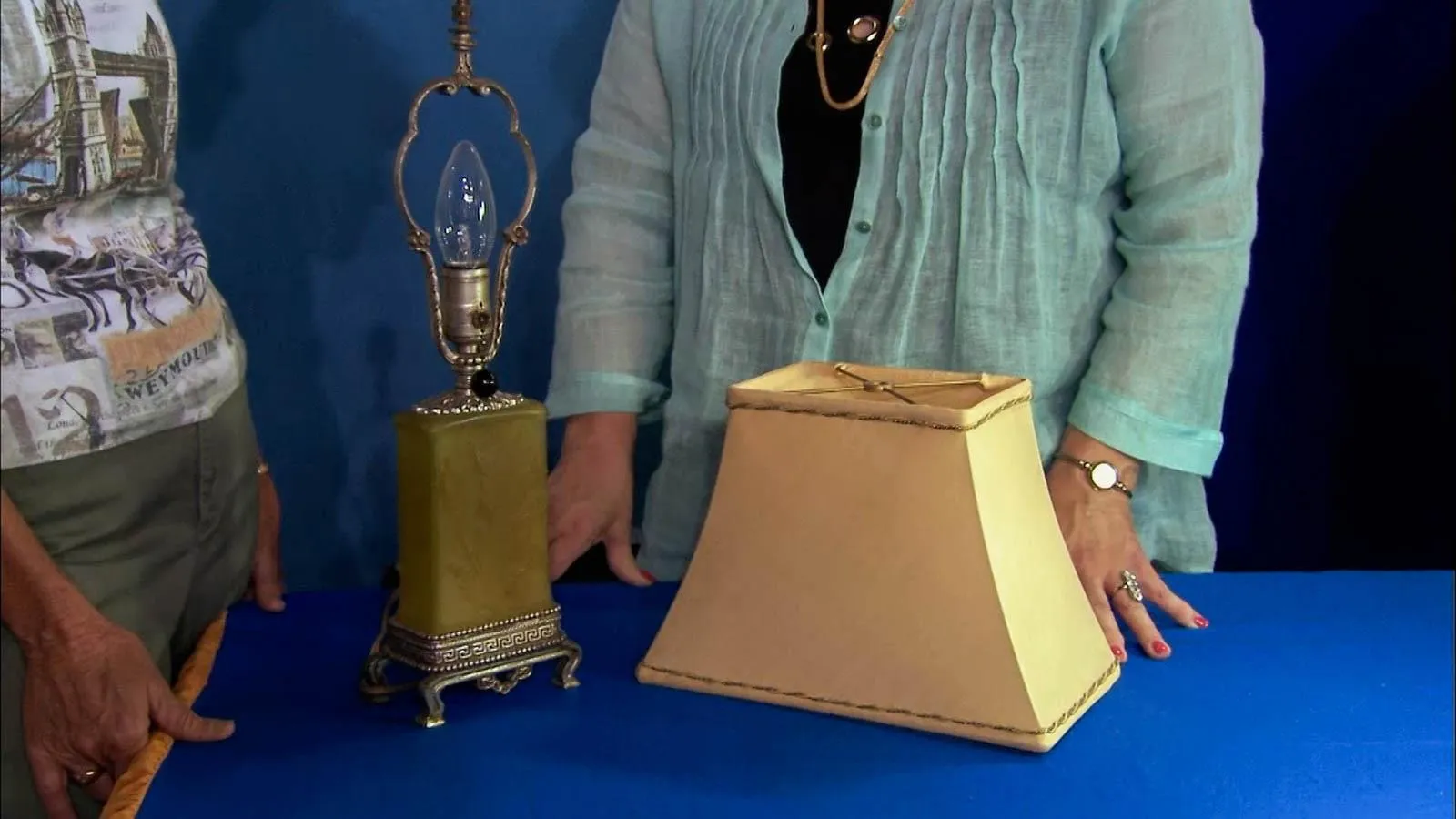 Green Jade lamp base with silver sockets sitting on a table next to a cream lamp shade.