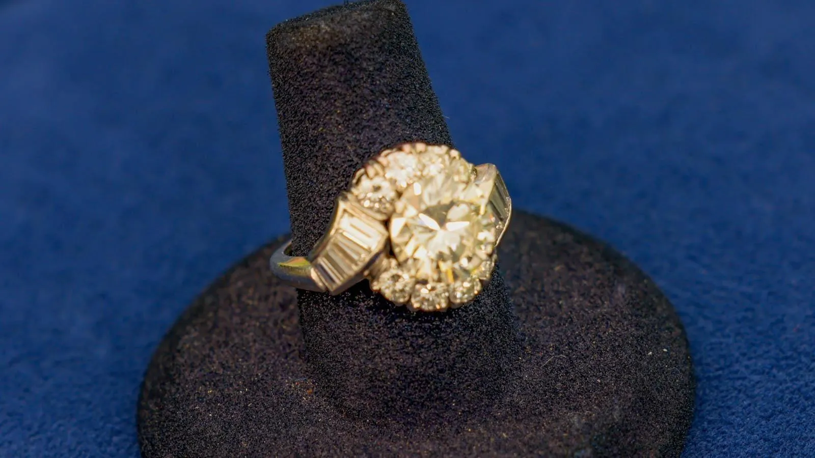 Close up of a ring with a platinum body. Has diamonds circulating its central gemstone.