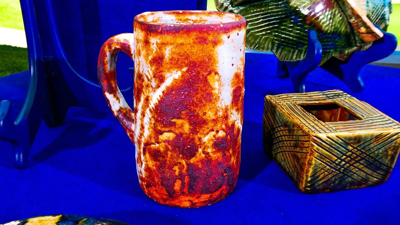 A mug with white and light brown marbeling sitting on a blue table.