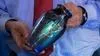 A man holding a blue and green iridescent vase with silver squiggle accents.