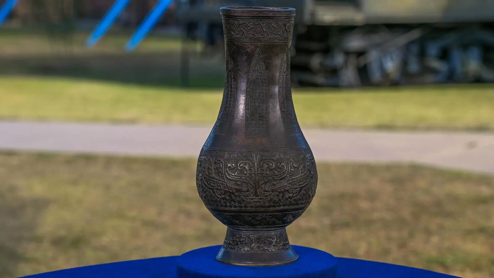 Close up of a dark bronze vase with detailing around the mouth and base.