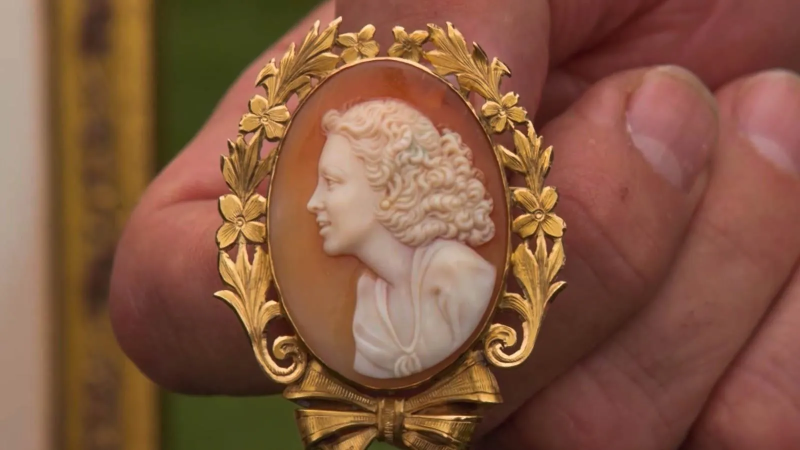 A close up of a silhouette of a woman on brooch  with a gilded border.