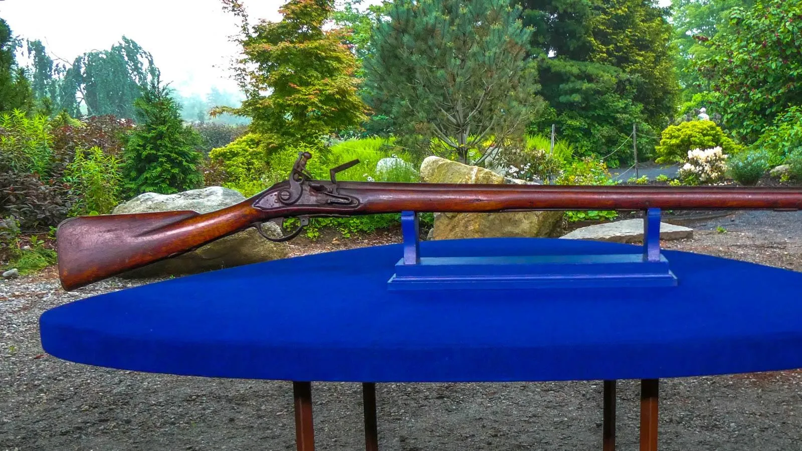 A long skinny dark wood gun is placed on top of a blue table.