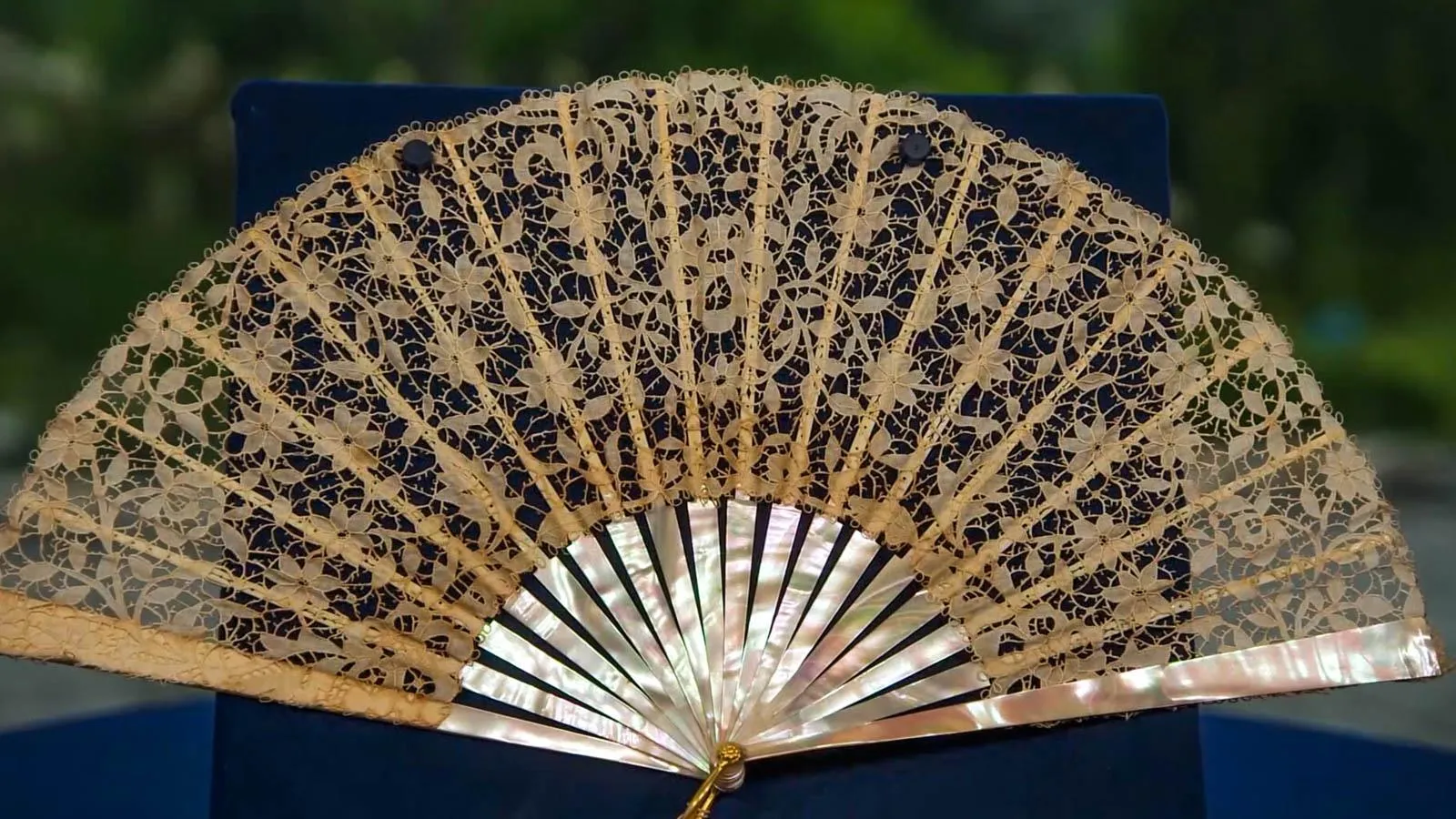 Close up on the fan open showing the yellowed lace detail on the peal fan frame.