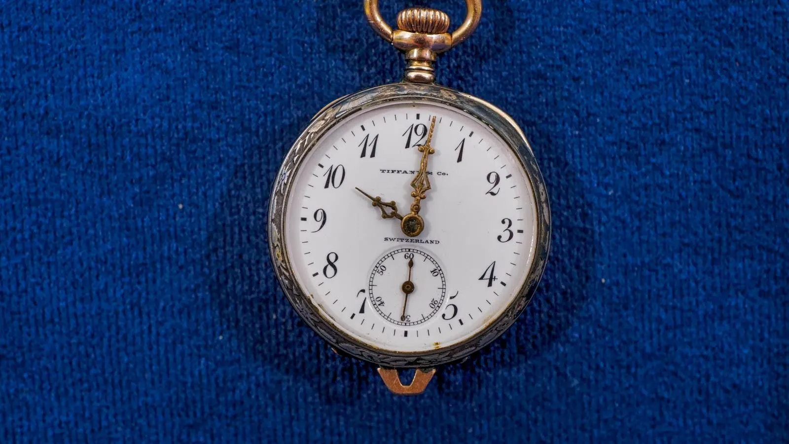 A  pocket watch with scripted watch face on blue background