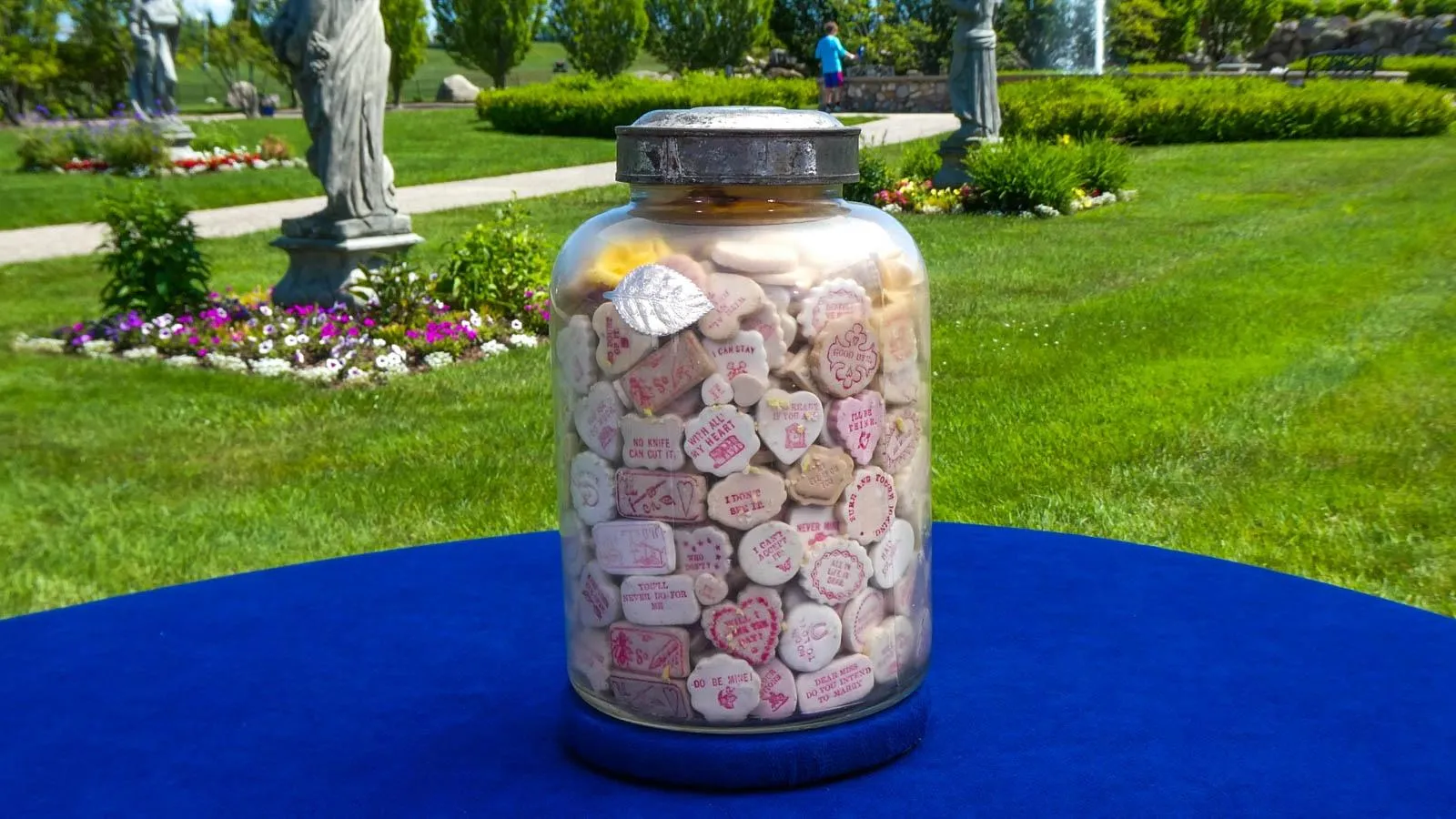 A large glass jar filled to the brim with conversation candy with red writting.