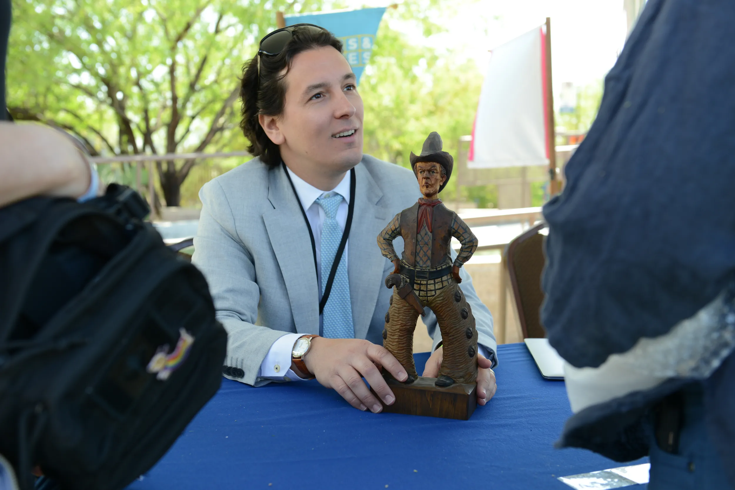 Toys and Games appraiser Michael Bertoia holds a small statue of a cowboy, with it's hands on it's hips, as he speaks to it's owner from the appraisal table.