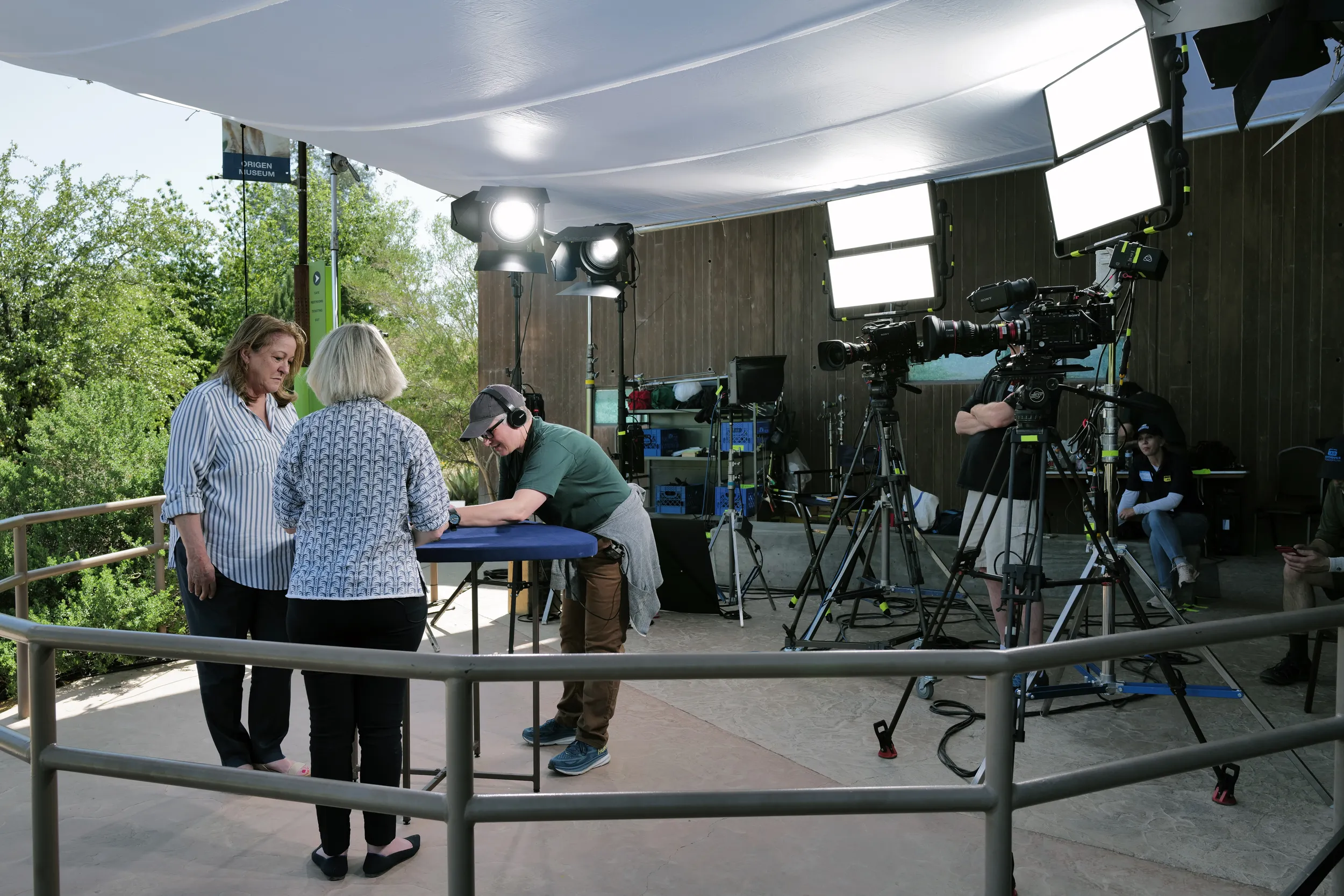A producer sets up an item on an appraisal table. She's surrounded by her crew and their equipment, ready to film.