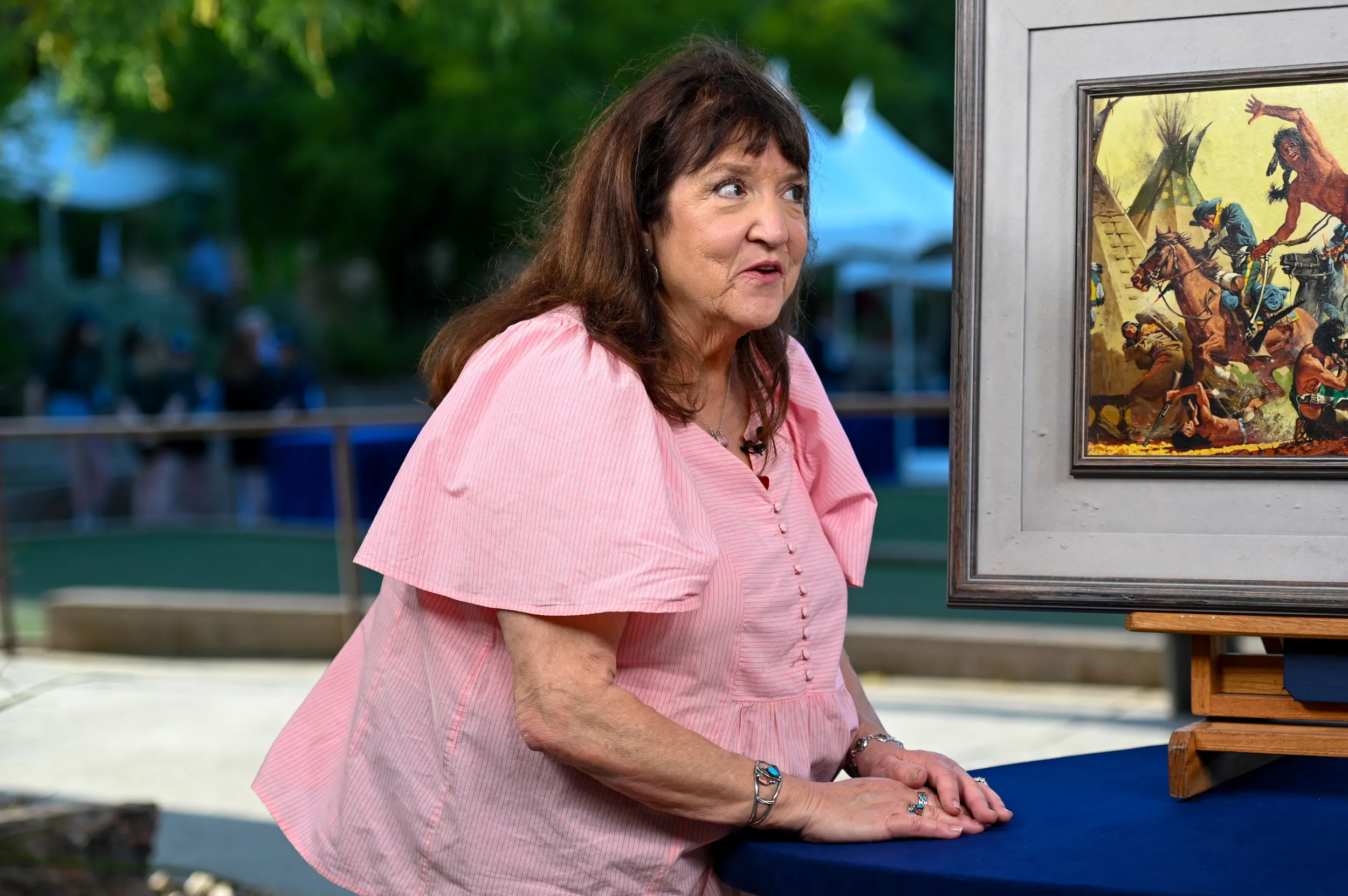 A guest smiles as her painting is appraised on camera.