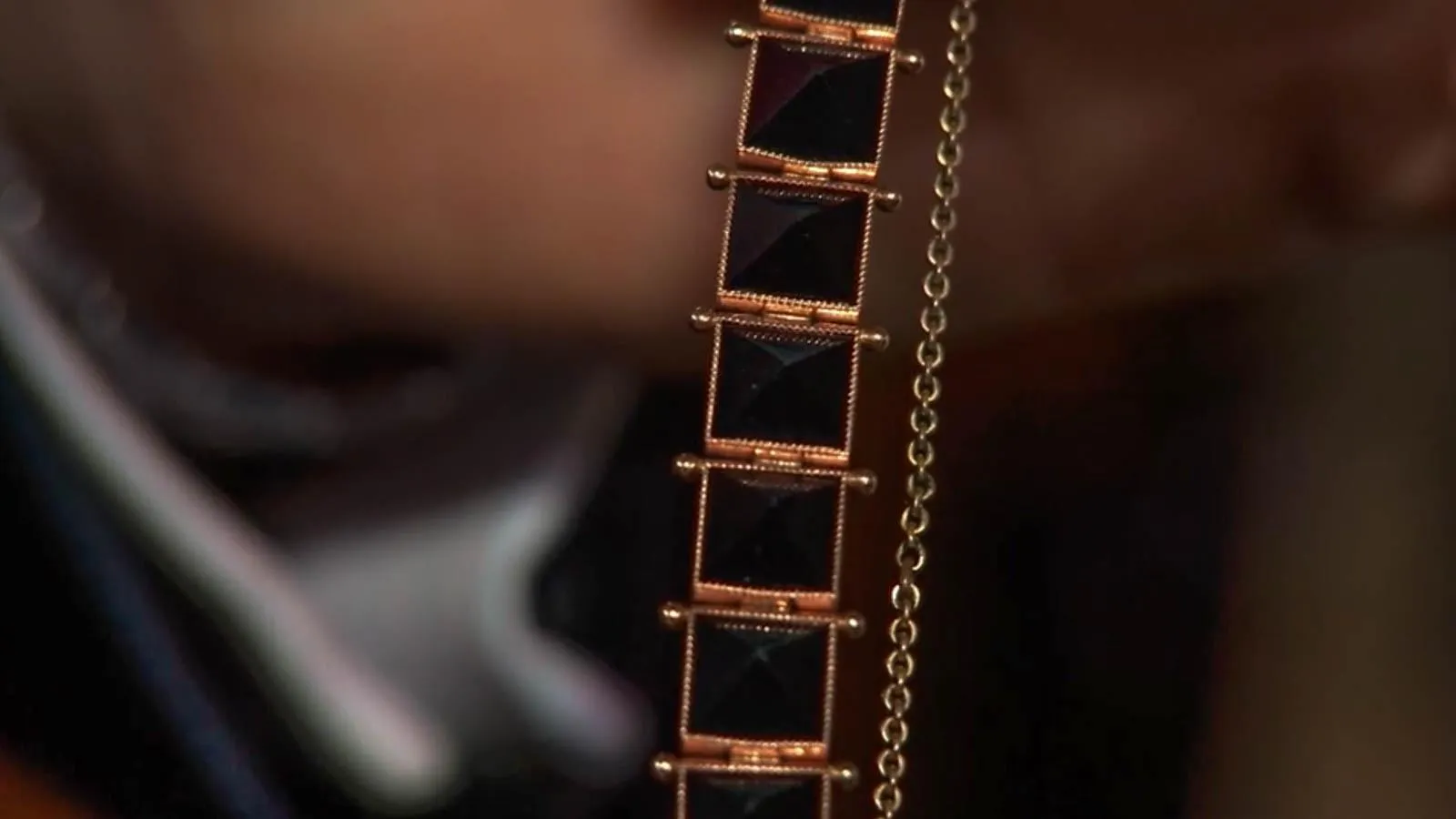 Close up of bracelet with rose gold links that hold together black squares design.