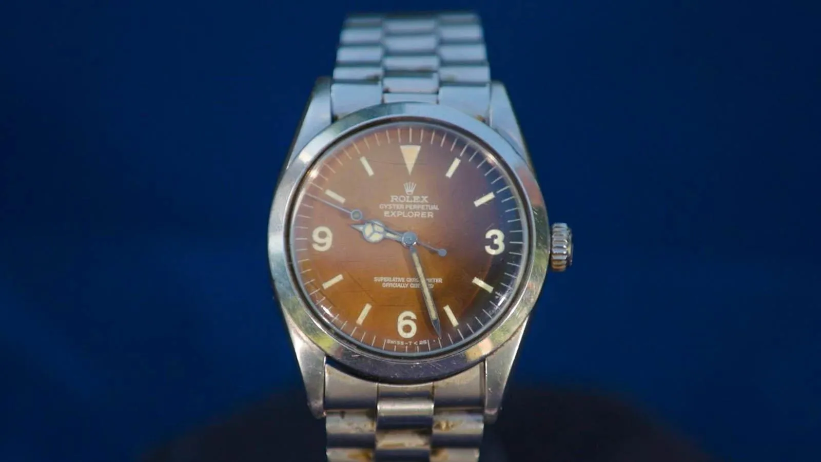 Close up of watch that has a silver bracelet strap and a light brown dial.