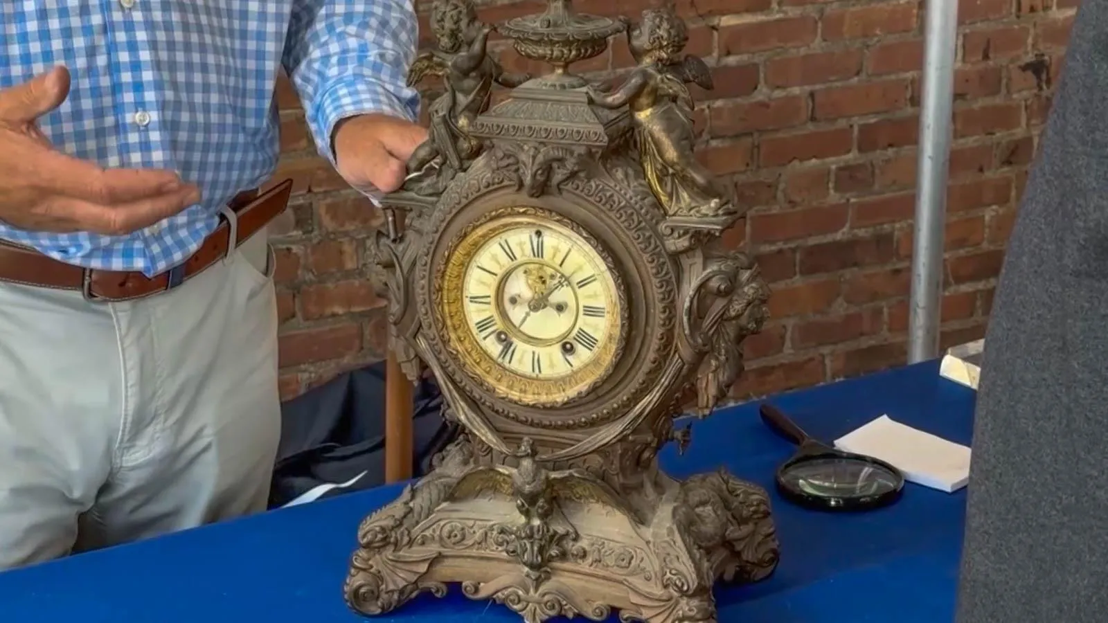 A gothic clocked on a blue table with a creme watch face.