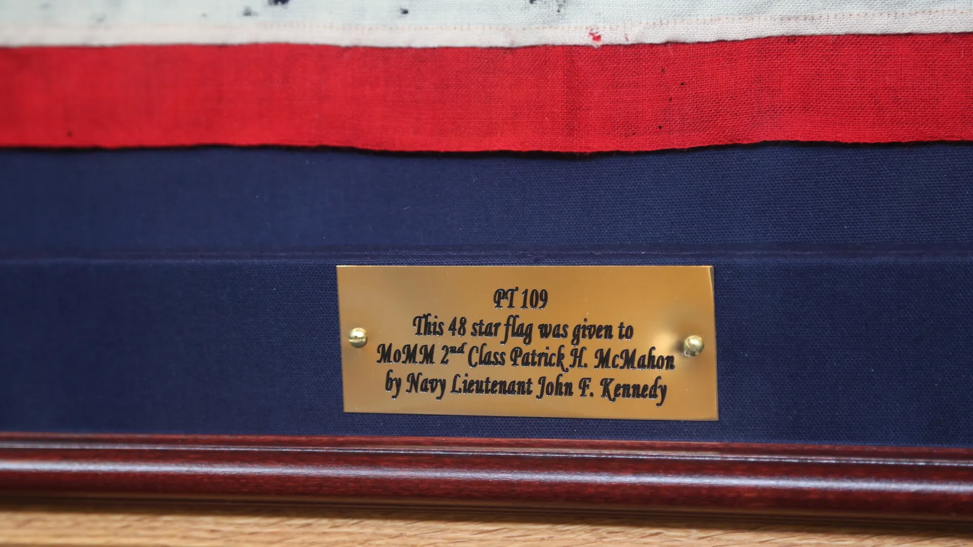 Close-up of inscribed plaque on framed flag