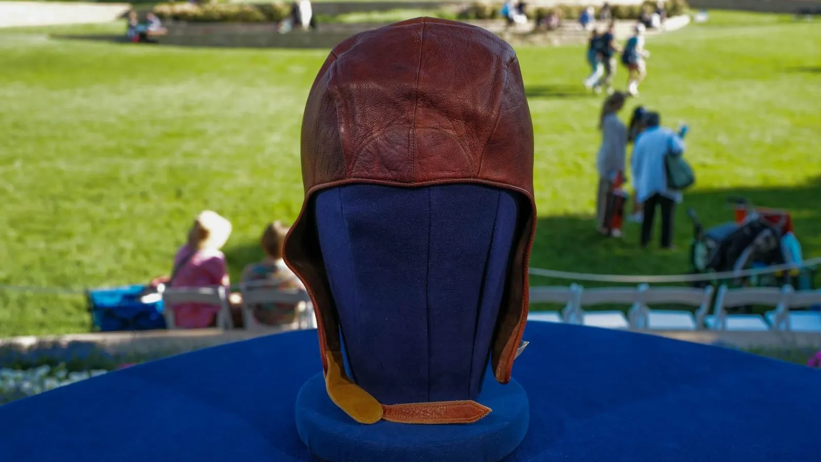 Close up of a leather headpiece that covers the back of the head, the forehead, and the ears, with leather straps hanging down each side.