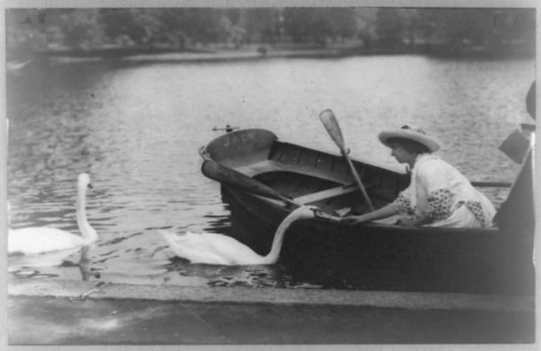 Helen Keller in a rowboat feeding a swan.