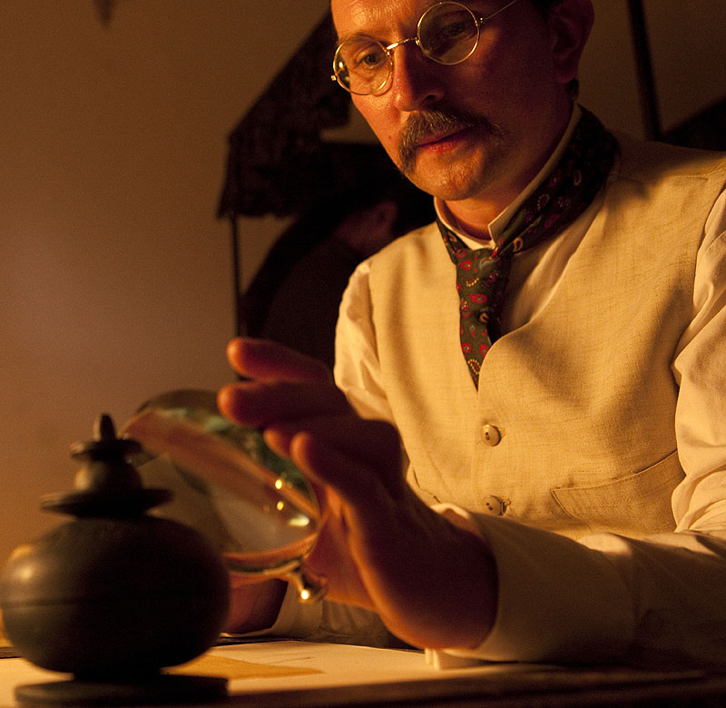 In a reconstructed sequence, estate manager William Peppe examines relics in a glass jar.