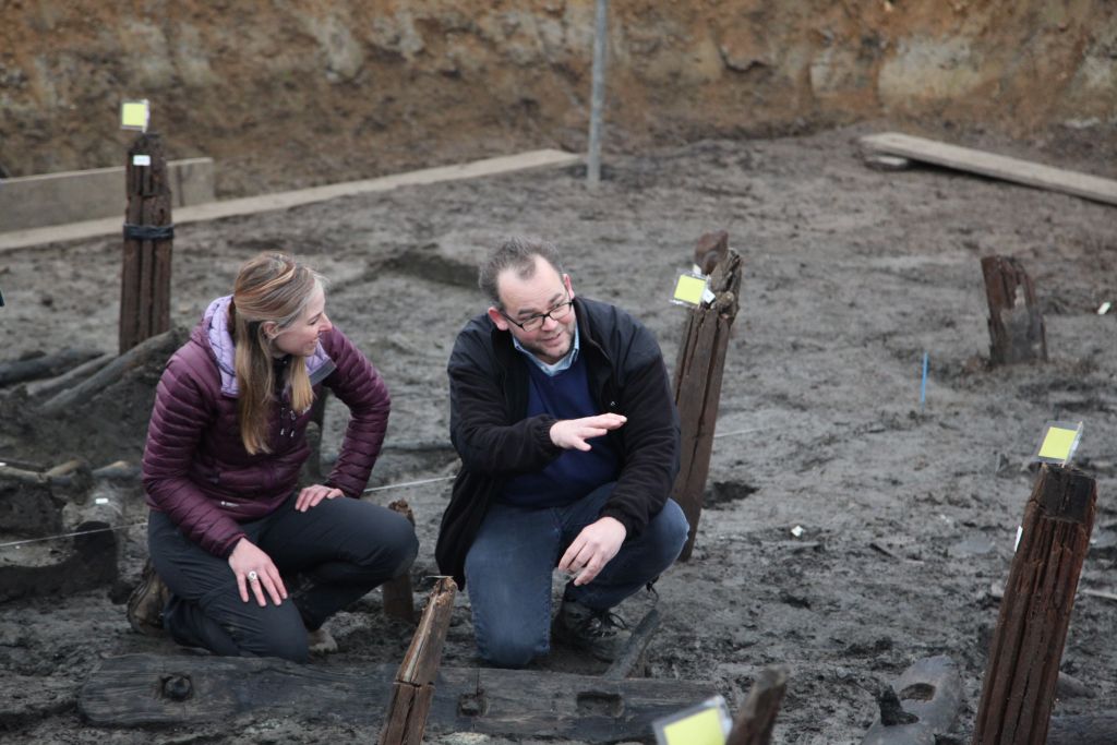 Alice Roberts kneeling and talking to Karl Harrison in a trench (Lake Constance)
