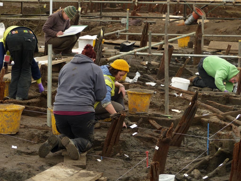 Five archaeologists in shot all working on different parts of the site