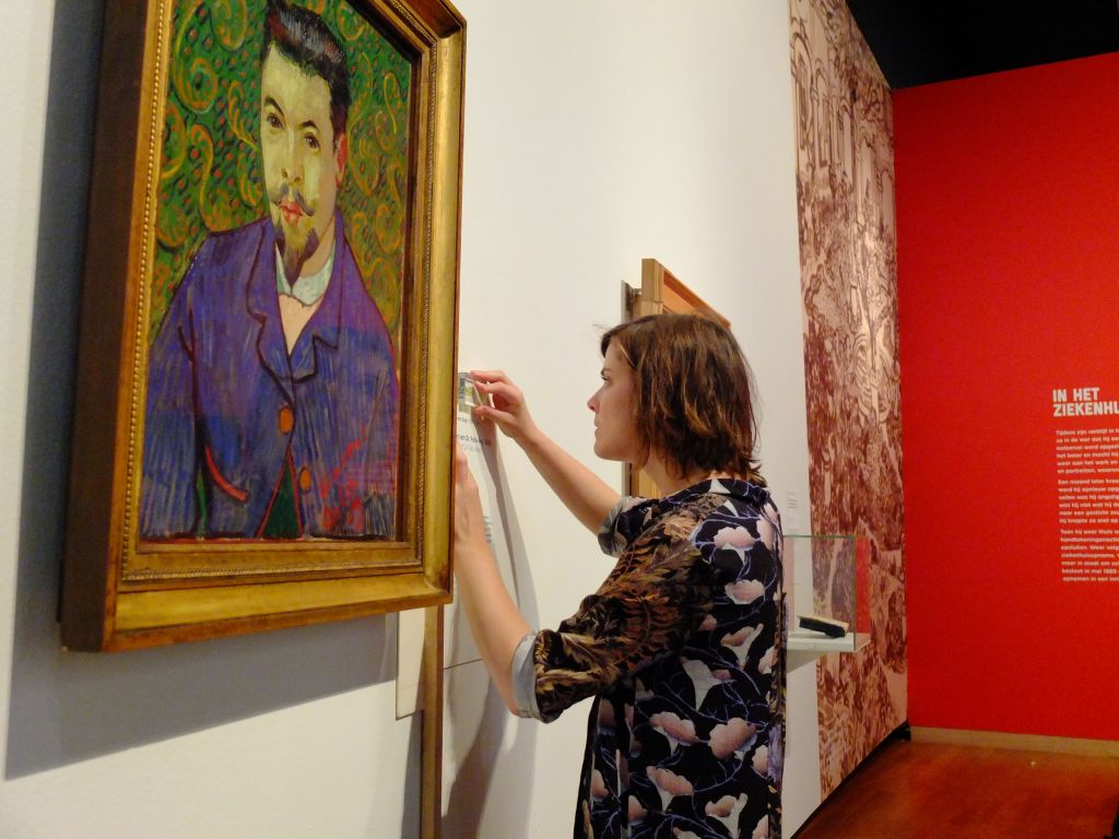 Labelling Van Gogh's Portrait of Dr Felix Rey, 1889 for the exhibition "On the Verge of Insanity:  Van Gogh & His Illness".  Painting in background soft focus is Still Life with a Plate of Onions, 1889, Vincent van Gogh