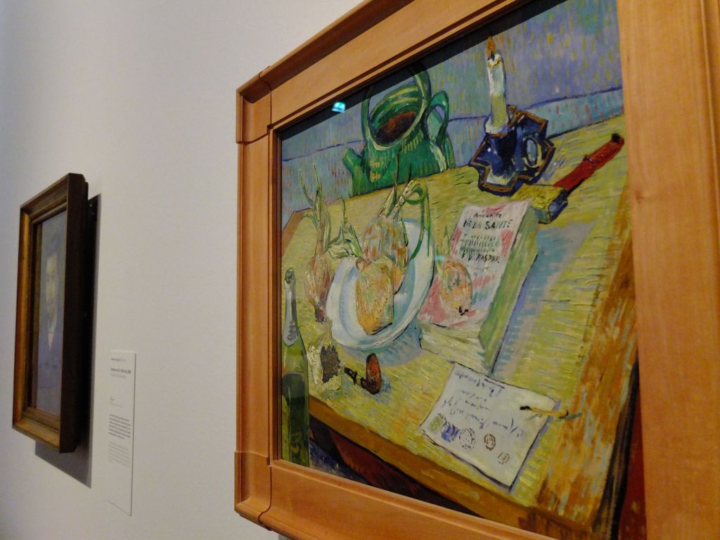 Still Life with a Plate of Onions, 1889, Vincent van Gogh in position for the exhibition "On the Verge of Insanity:  Van Gogh & His Illness".  Painting in background soft focus is Portrait of Dr. Felix Rey, 1889